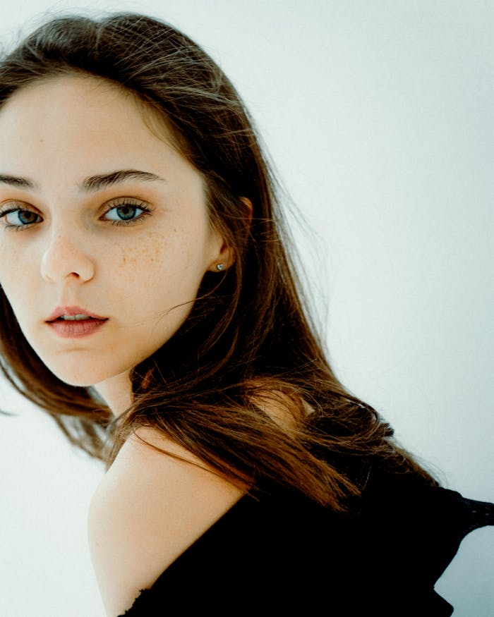 services-02 A close-up portrait of a young woman with freckles and natural expression, exuding beauty and elegance.