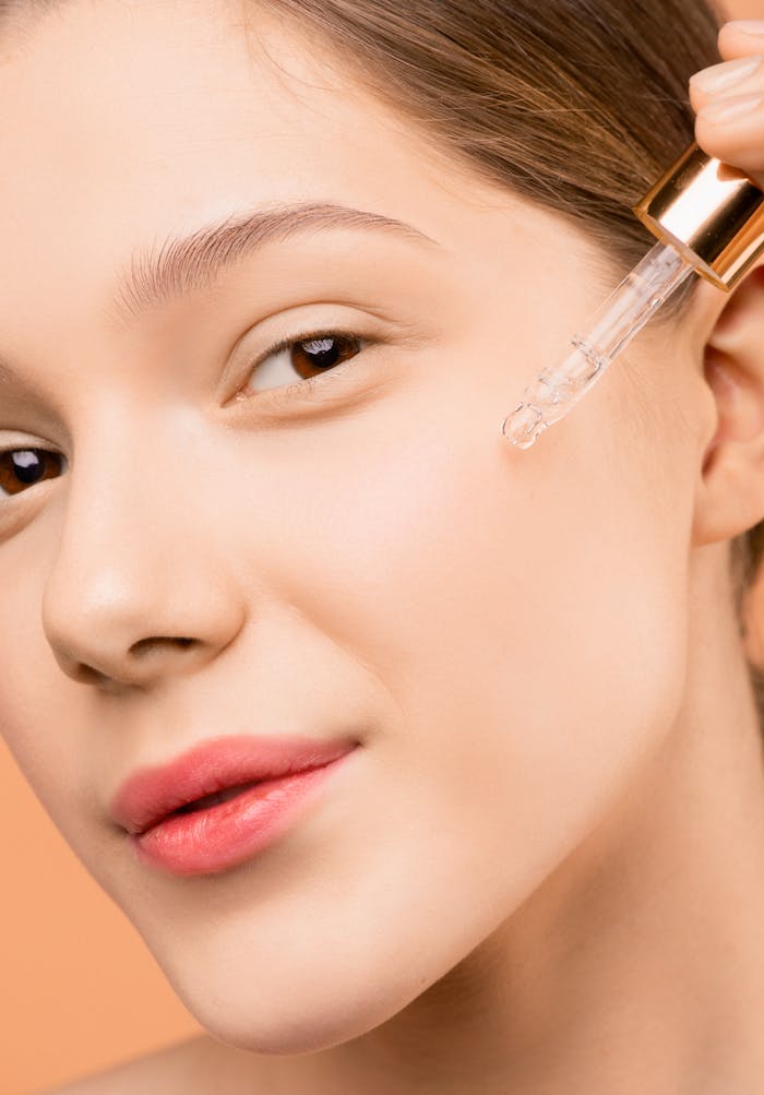 journey A woman applying serum with a dropper to her face for skincare routine.