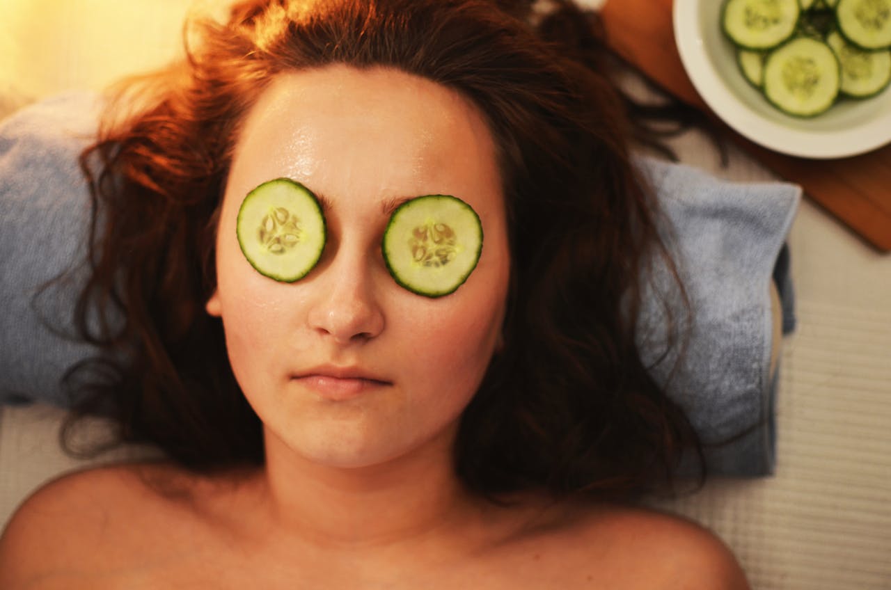Woman enjoying a relaxing cucumber facial treatment at a spa for skin care and rejuvenation.